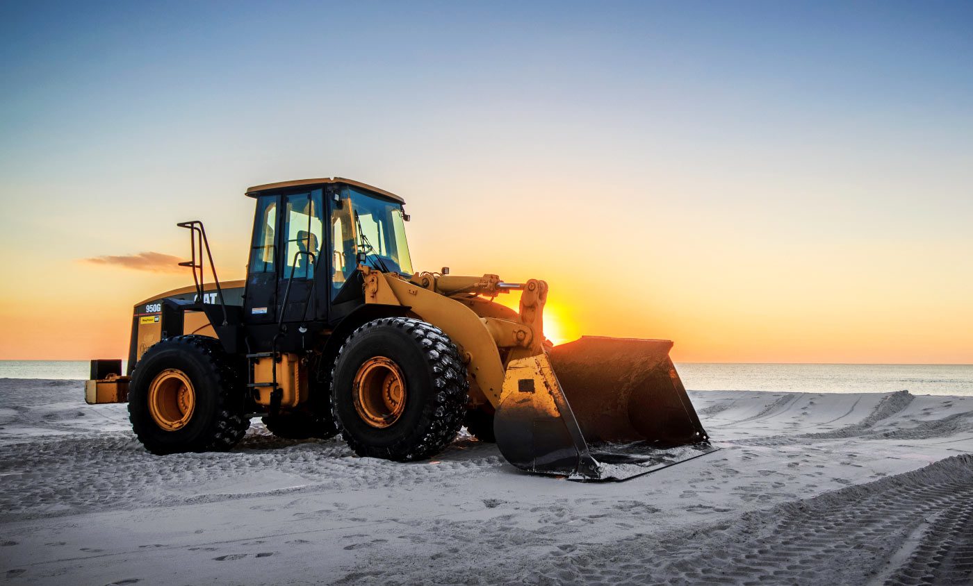 A yellow and black tractor is parked on the beach