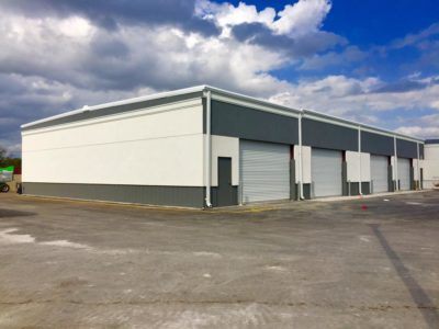 A large warehouse with two doors and a sky background