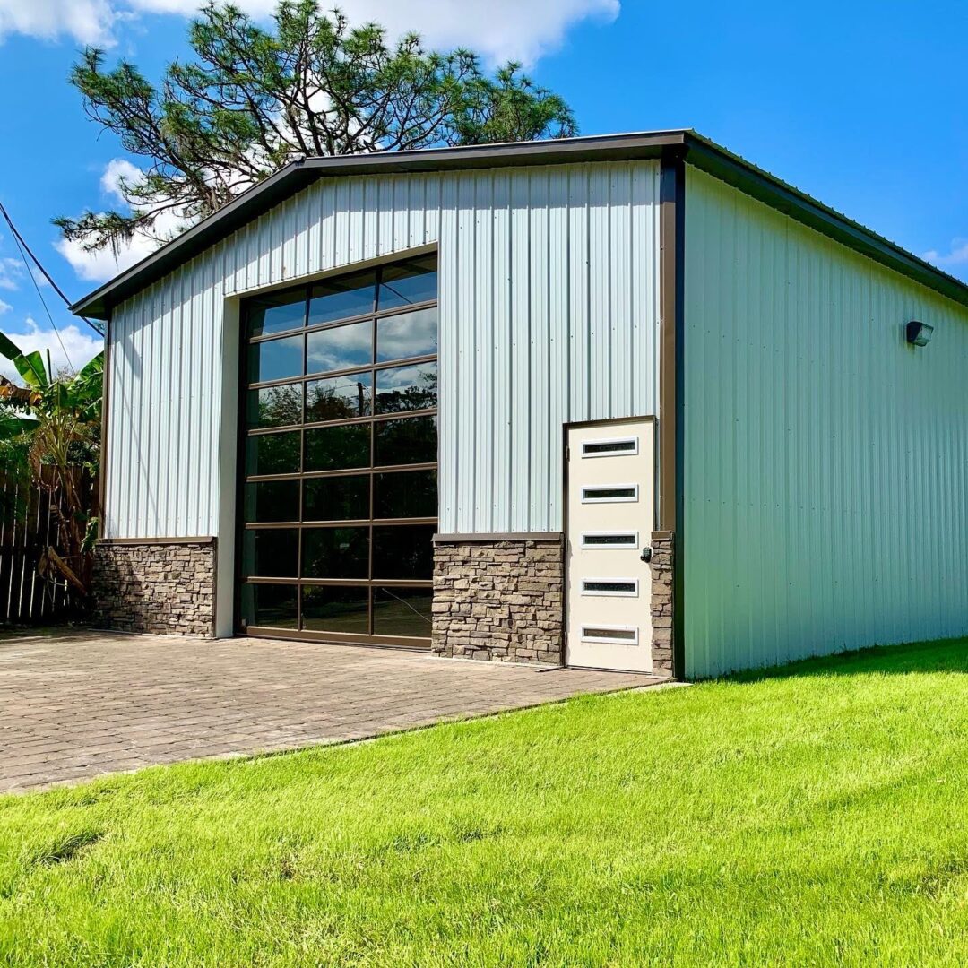 A large garage with a door open and grass in front of it.